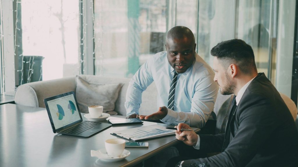 Dos consultores revisan gráficos en una laptop durante una reunión
