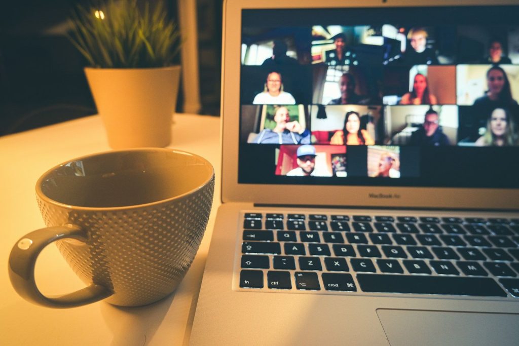 Videollamada con muchos participantes en una laptop junto a una taza
